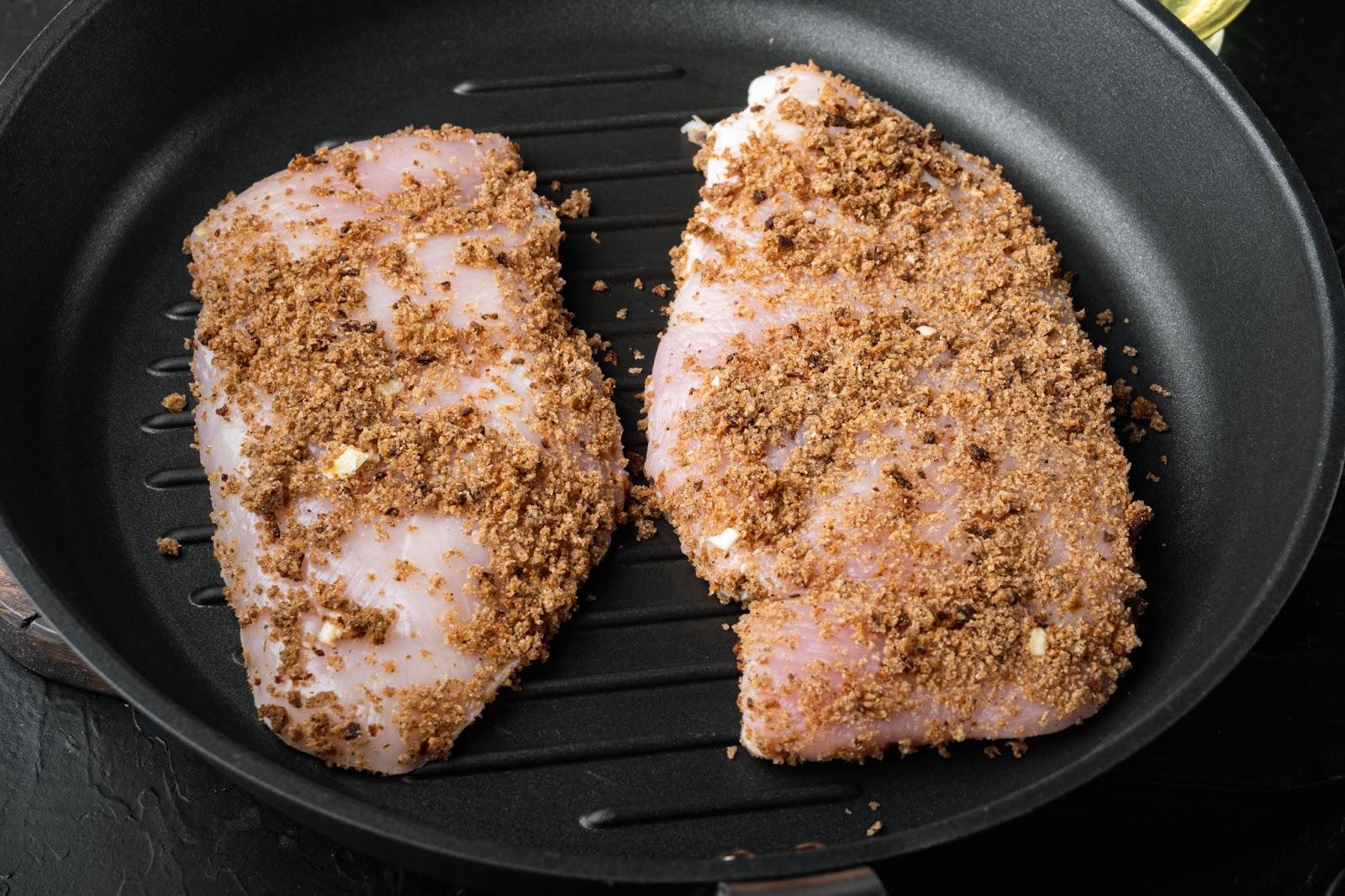 chicken cutlets being placed in a slightly greased oven dish