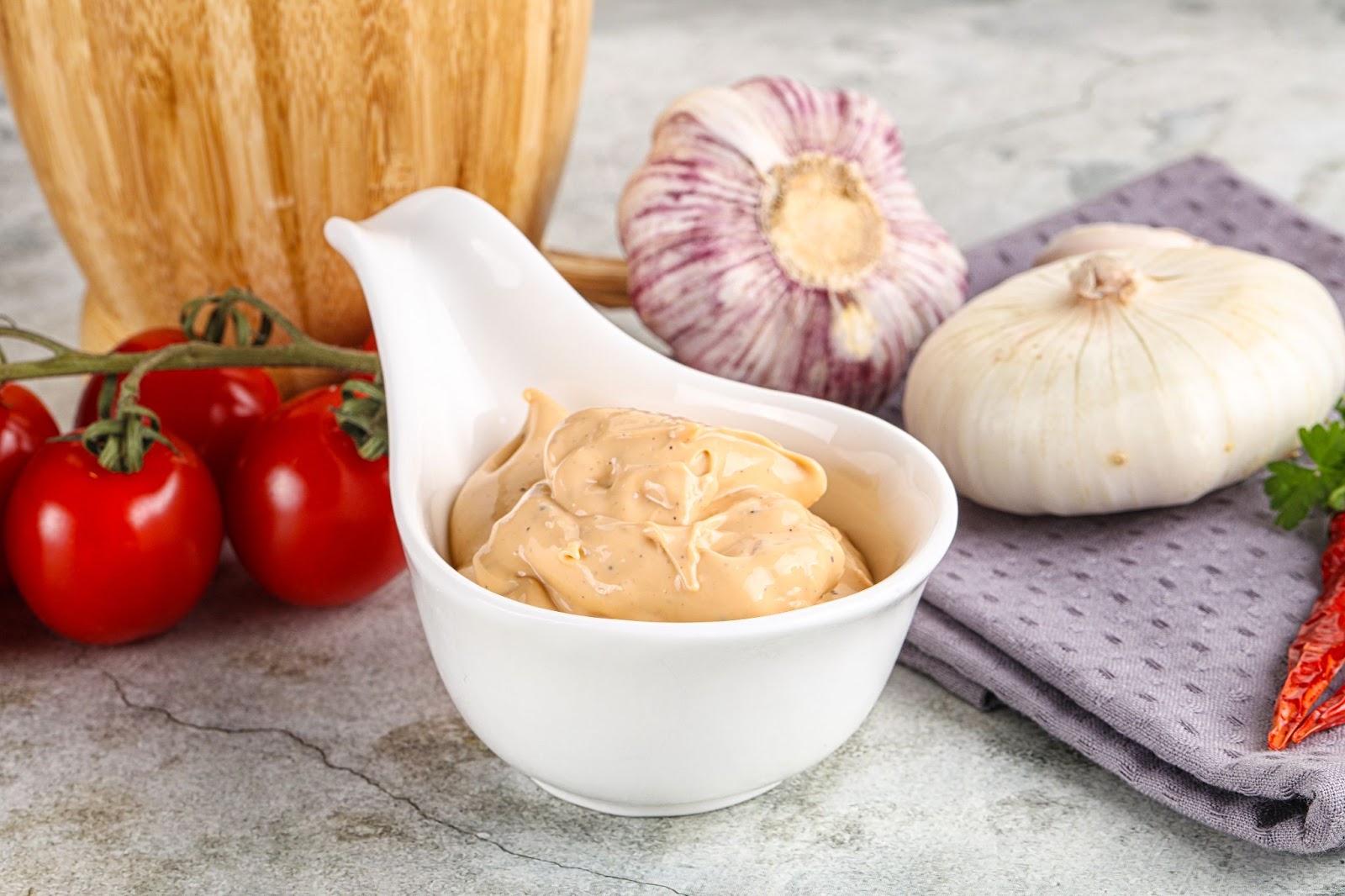 Sriracha Mayo served in a small bowl surrounded with onions and tomatoes