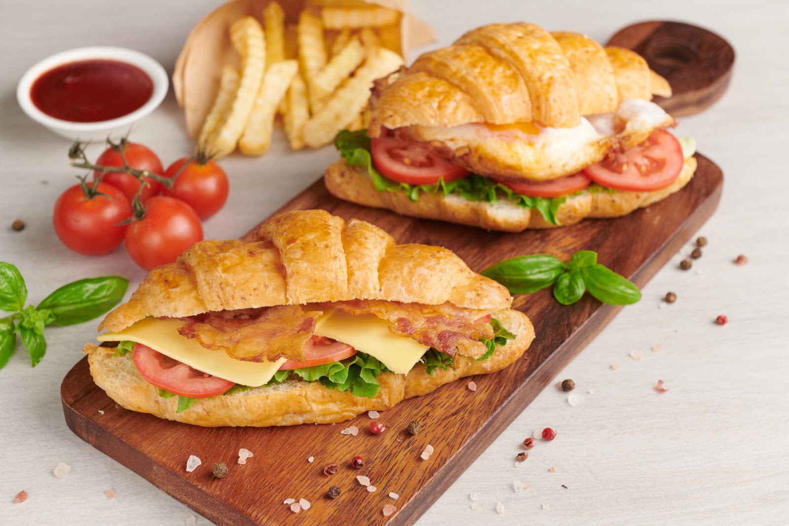 Brioche sandwiches placed on a wooden board along with fries and sauce