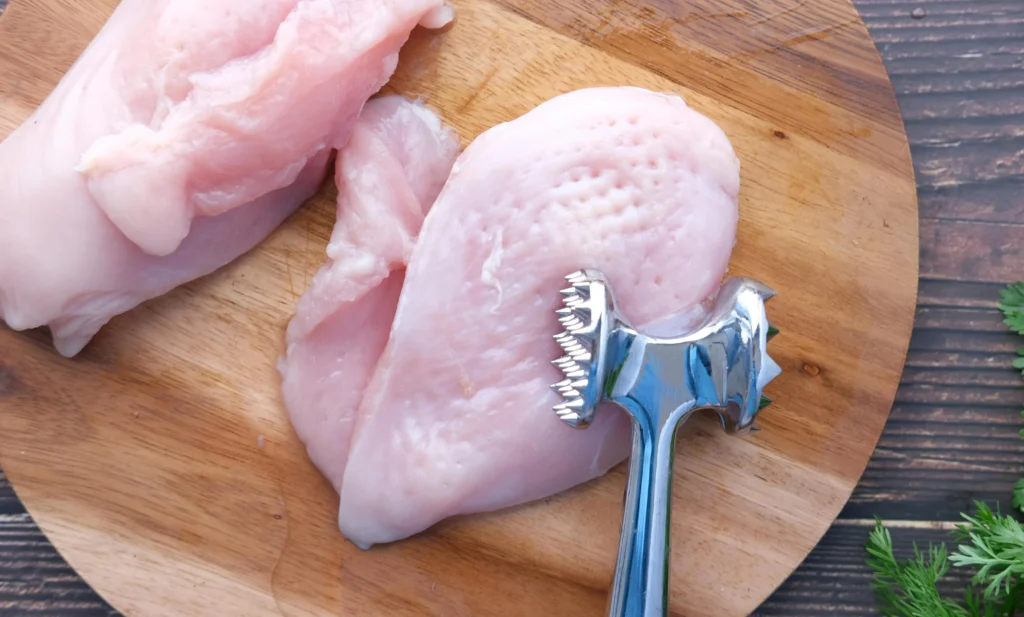 Raw chicken breast being pounded