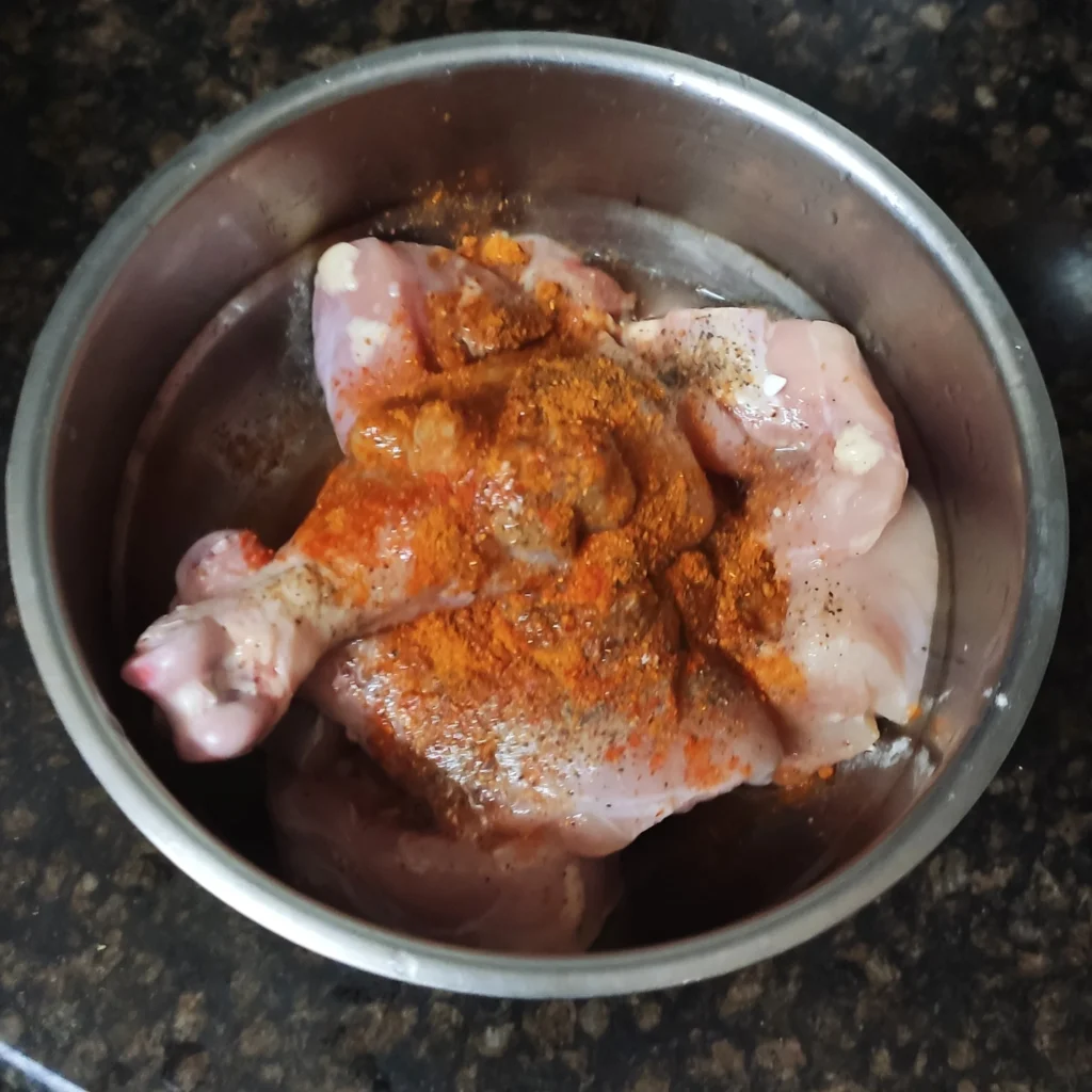 Raw chicken with spices in bowl.