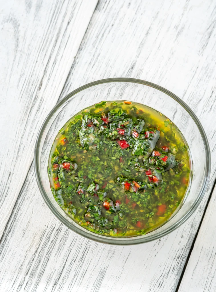 green chimichurri sauce in a bowl on wooden table