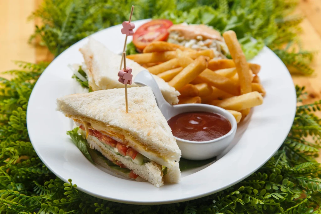cutlet sandwich served in white plate with fries and sauce