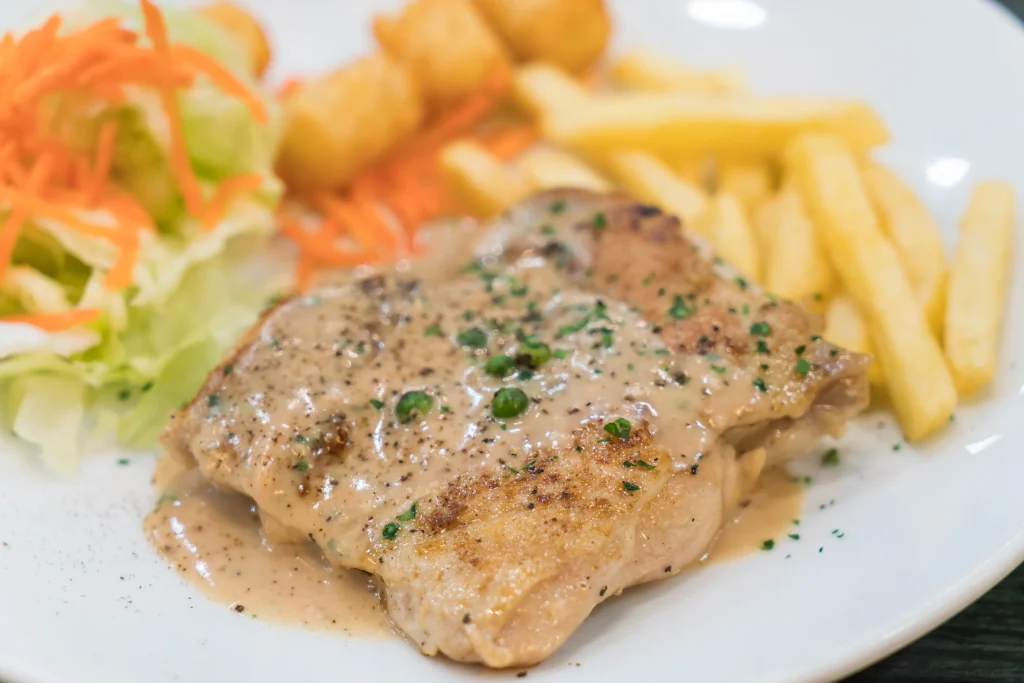 crispy cutlet with gravy served in a white plate with fries and veges