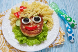 Plate of air fryer cutlets for kids recipe with pasta face and vegetables