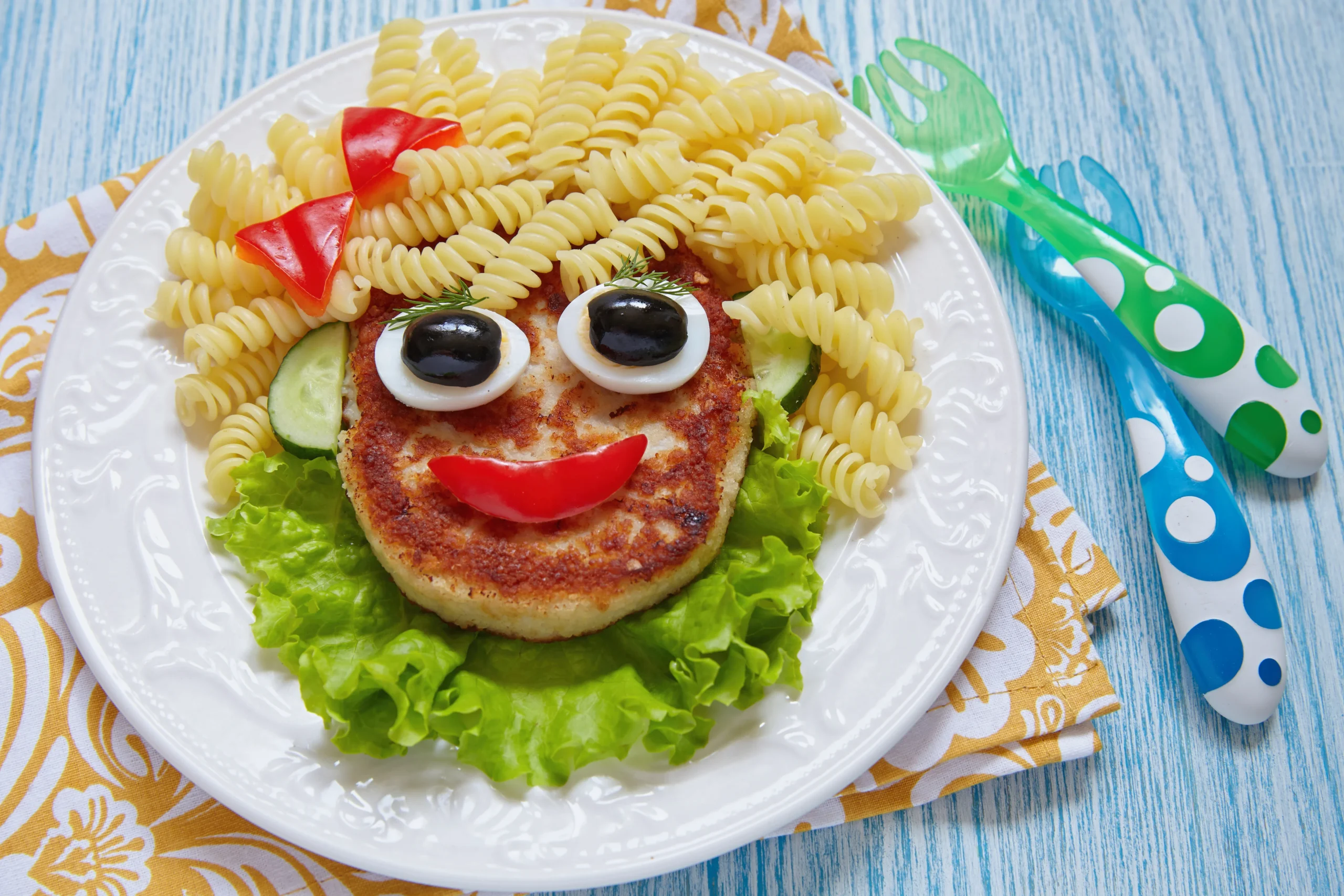 Plate of air fryer cutlets for kids recipe with pasta face and vegetables