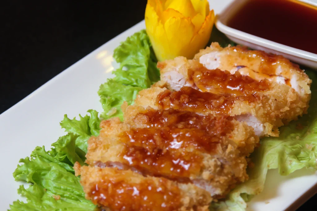 hot honey chicken cutlets being served in white plate with sauce and lettuce